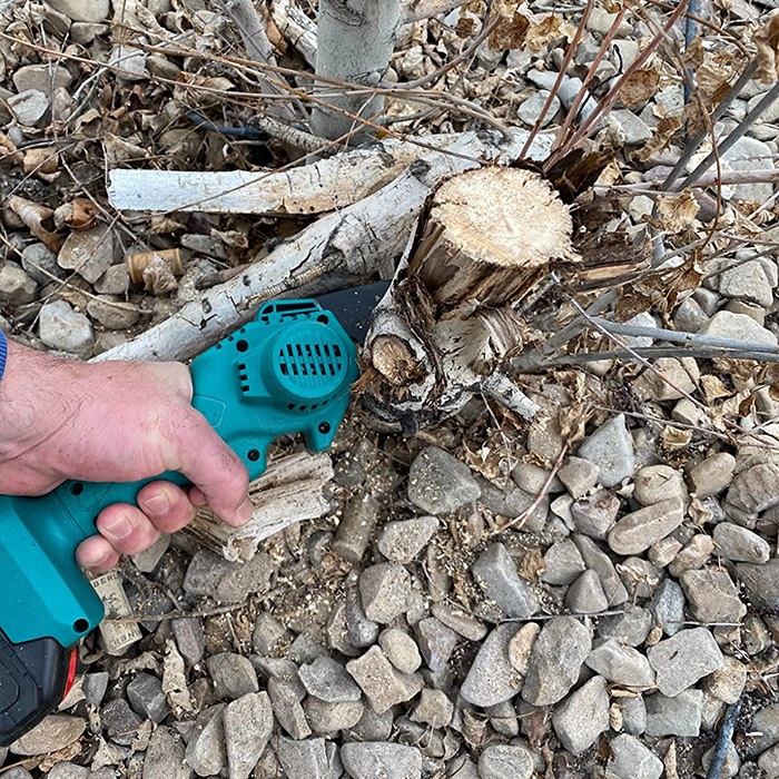 Mężczyzna tnący drewno mini piłą